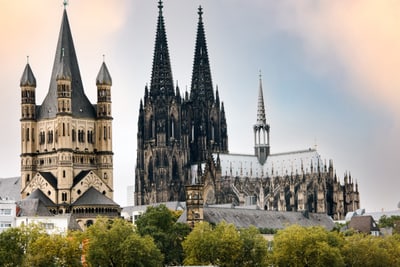 Historische Kathedrale und Kirche mit Türmen und Bäumen im Vordergrund.