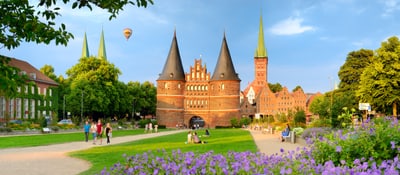 Holstentor in Lübeck mit Blumen und Personen im Vordergrund.