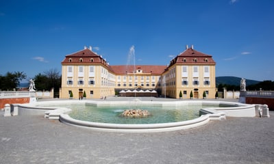 Grosses gelbes Gebäude mit Brunnen und Blauer Himmel.