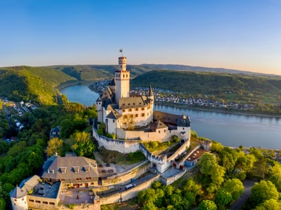 Luftaufnahme eines Schlosses am Fluss, umgeben von Hügeln.