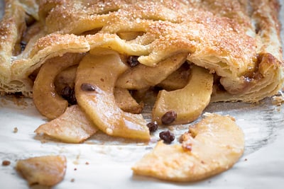 Nahaufnahme von geschnittenem Apfelstrudel mit Blätterteig und Rosinen.