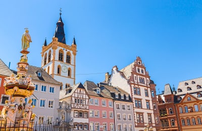 Historische Gebäude und ein verzierter Brunnen unter klarem Himmel.