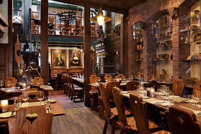 Rustikales Restaurantinterieur mit Holzmöbeln und Gemälden.