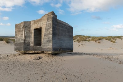 Alter Betonbunker in sandiger Dünenlandschaft.