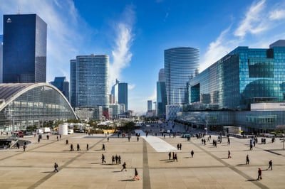 Stadtplatz mit modernen Hochhäusern und Menschen bei sonnigem Himmel.