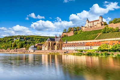 Blick auf Fluss, historische Gebäude und Festung auf Hügel.