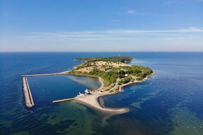 Luftaufnahme einer kleinen Insel mit grünem Bewuchs im Meer.