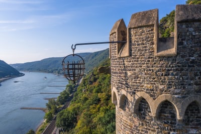Mittelalterlicher Turm am Rhein mit Gitterkäfig über dem Fluss.