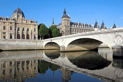 Historische Gebäude und Brücke über einem Fluss an einem sonnigen Tag.