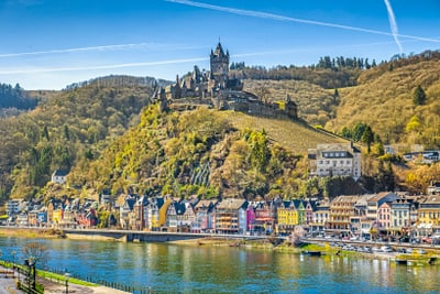 Burg auf Hügel über malerischer Stadt am Flussufer.