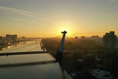 Sonnenuntergang hinter einer modernen Brücke über einem Fluss in einer Stadt.