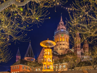 Illuminierte Gebäude und Bäume bei Nacht, beleuchteter Turm im Vordergrund.