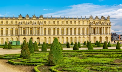 Historisches Gebäude mit gepflegtem Garten und Hecken im Vordergrund.