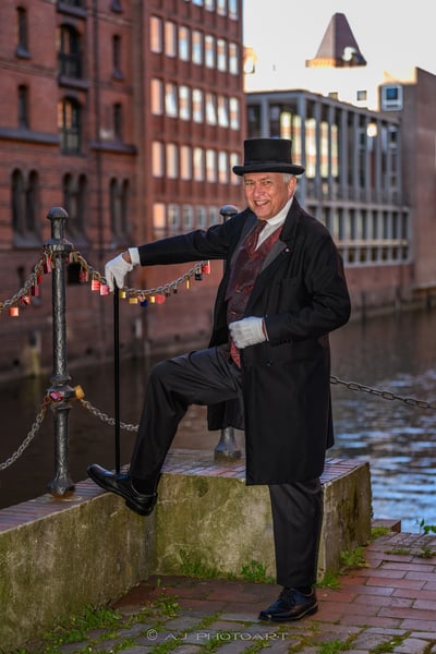 Mann in historischer Kleidung mit Zylinder und Stock am Kanal.