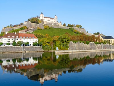 Festung auf Hügel mit Spiegelung im Fluss.