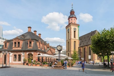 Historische Gebäude und Kirchturm auf Stadtplatz bei sonnigem Wetter.