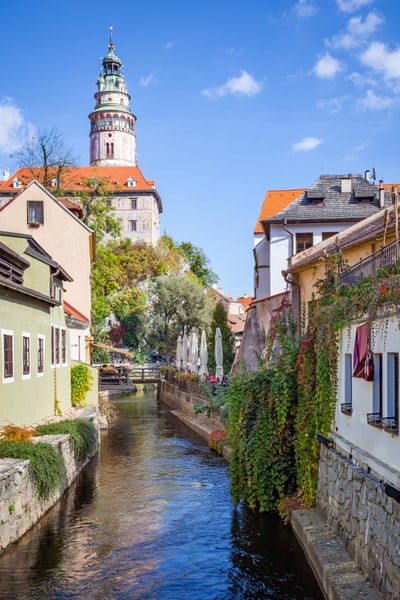 Malerischer Kanal mit historischen Gebäuden und einem Turm im Hintergrund.