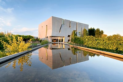 Modernes Gebäude mit Wasserreflektion im Vordergrund.