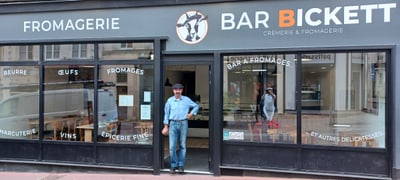Mann steht vor einer Fromagerie namens Bar Bickett.