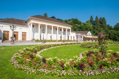 Historisches Gebäude mit formellen Gärten im Vordergrund.