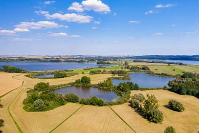 Luftaufnahme von Feldern, Wäldern und Seenlandschaft.
