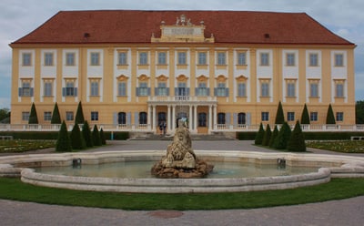 Grosses historisches Gebäude mit rotem Dach und Springbrunnen im Vordergrund.