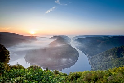 Landschaft mit Flussbiegung und Sonnenaufgang.