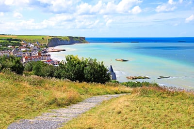 Pfad führt zu Küste mit Klippen, Dorf und Meer.