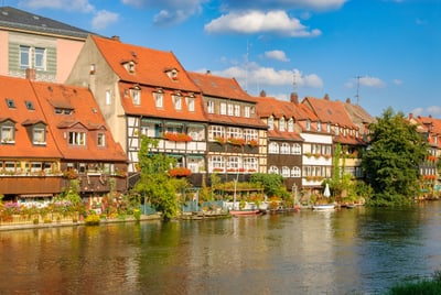 Fachwerkhäuser mit roten Dächern am Flussufer.
