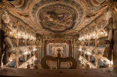 Barocker Opernsaal mit reich verziertem Deckenfresko und Balkonen.