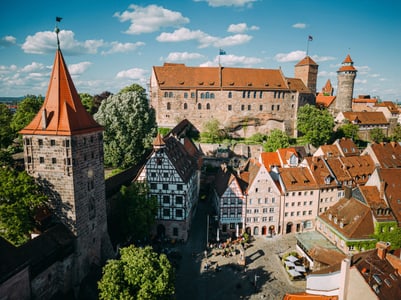 Luftbild einer mittelalterlichen Burg und Stadt mit roten Ziegeldächern.