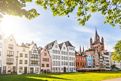 Bunte Häuserreihe und Kirche am sonnigen Tag.