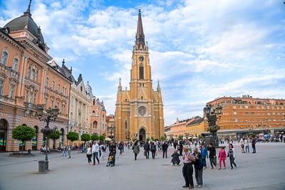 Belebter Platz mit grossen historischen Gebäuden und einer Kirche im Hintergrund.