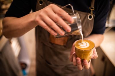 Barista giesst Milchschaum in Kaffee.