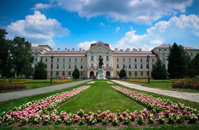 Schloss mit gepflegten Blumenbeeten und blauem Himmel.