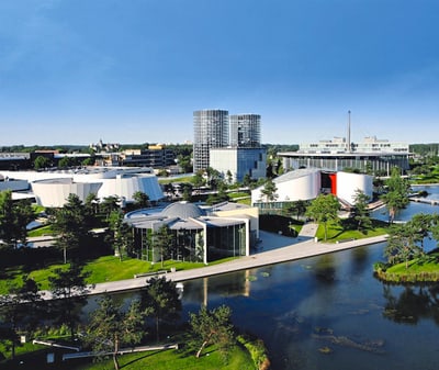 Moderne Gebäude und Landschaft bei Sonnenschein, mit Wasserflächen.