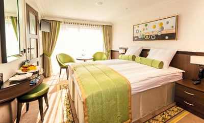 twerenbold_36823.jpg Hotelzimmer mit grünem Dekor und Doppelbett.