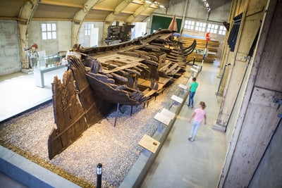 Besucher betrachten ein antikes Schiffswrack in einem Museum.