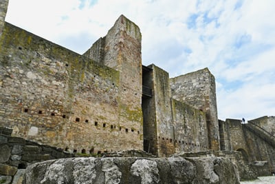Alte Steinmauern einer historischen Festung mit bewölktem Himmel.