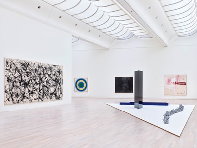 Heller Galerieraum mit verschiedenen abstrakten Kunstwerken an den Wänden.
