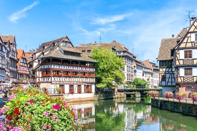 Malebene Fachwerkhäuser an einem Kanal mit Blumen und Brücke.