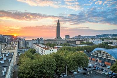 Stadtpanorama bei Sonnenuntergang mit Turm und Bäumen.