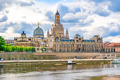 Historisches Gebäude an einem Flussufer mit bewölktem Himmel.